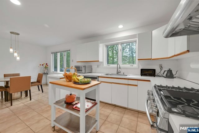 kitchen with exhaust hood, appliances with stainless steel finishes, a sink, light countertops, and light tile patterned flooring