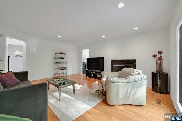 living room with recessed lighting, a tile fireplace, and light wood-style floors