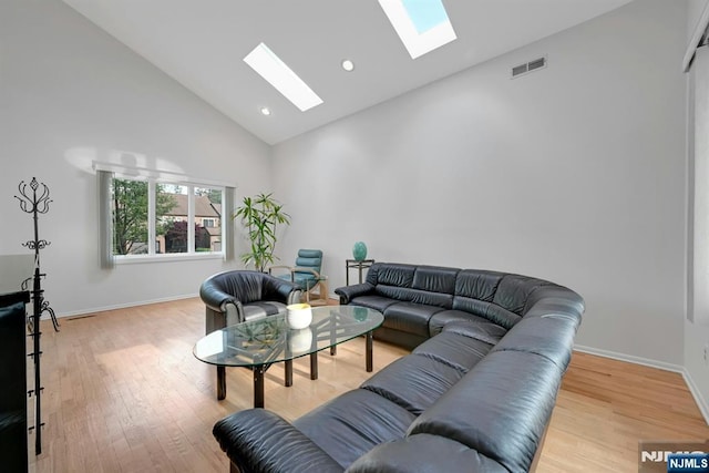 living area featuring visible vents, high vaulted ceiling, wood finished floors, and a skylight
