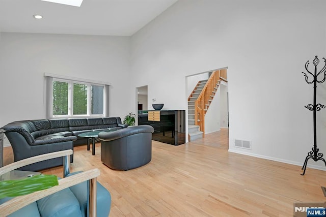 living room with visible vents, wood finished floors, stairway, high vaulted ceiling, and baseboards