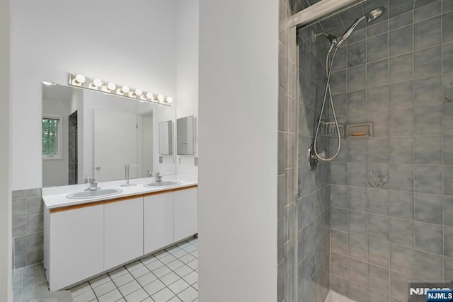 bathroom with double vanity, a sink, tile patterned flooring, and tiled shower