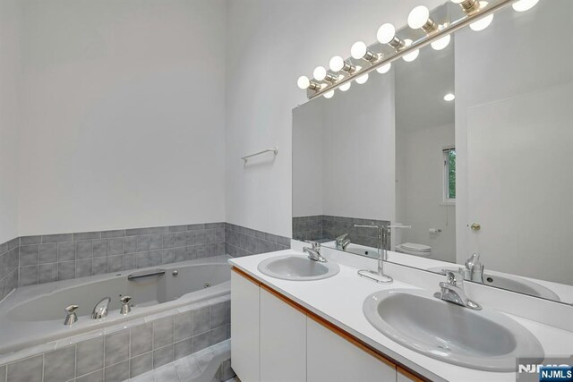 bathroom with a sink, a tub with jets, and toilet