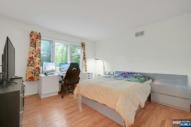 bedroom with light wood finished floors and visible vents