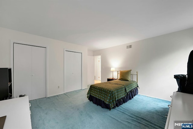 bedroom with multiple closets, carpet, and visible vents