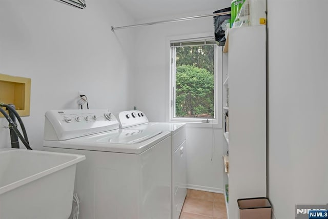 clothes washing area with light tile patterned floors, laundry area, washing machine and dryer, and a sink