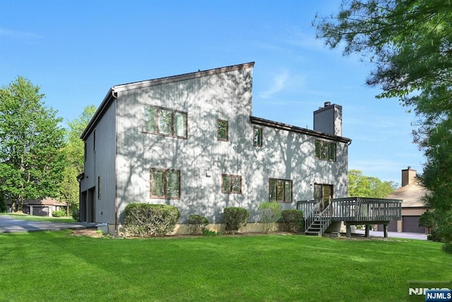 exterior space with an attached garage, a wooden deck, a yard, and a chimney
