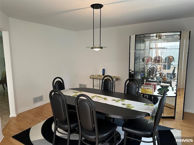 dining area featuring baseboards, visible vents, and light wood finished floors