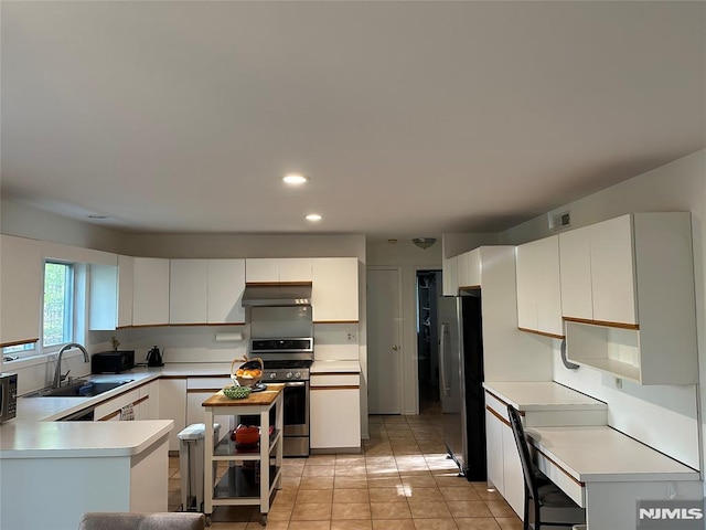 kitchen featuring visible vents, a sink, light countertops, under cabinet range hood, and stainless steel appliances