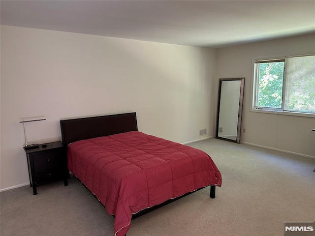 bedroom featuring baseboards, light carpet, and visible vents
