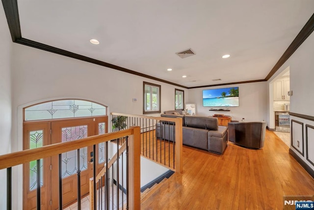 living room featuring crown molding, visible vents, and light wood-style flooring
