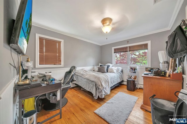 bedroom with ornamental molding, wood finished floors, and a wainscoted wall