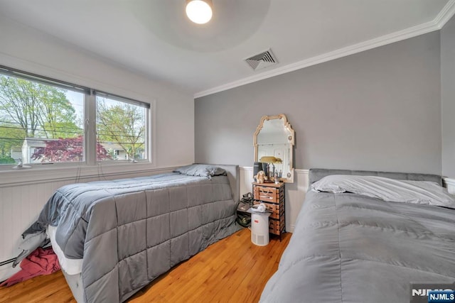 bedroom featuring visible vents, crown molding, and wood finished floors
