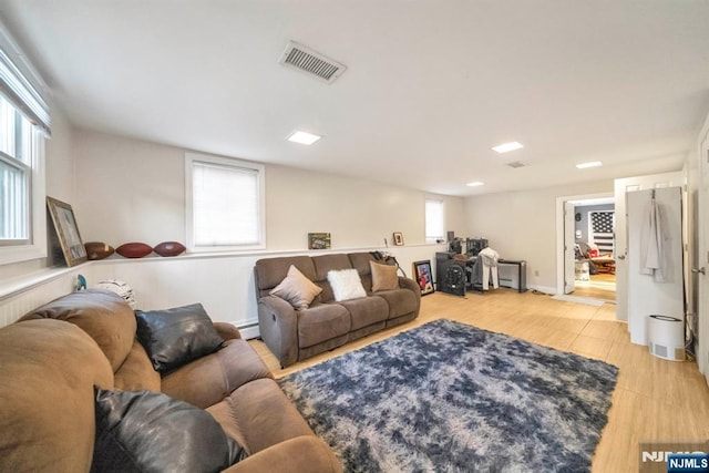 living area featuring visible vents, a baseboard radiator, and a wealth of natural light