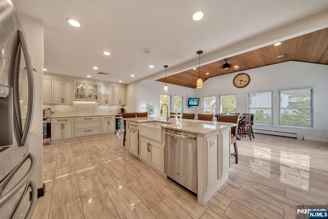 kitchen featuring a sink, lofted ceiling, stainless steel appliances, recessed lighting, and cream cabinetry