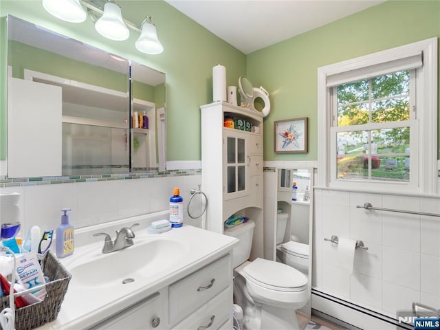 bathroom featuring wainscoting, vanity, toilet, tile walls, and a baseboard radiator
