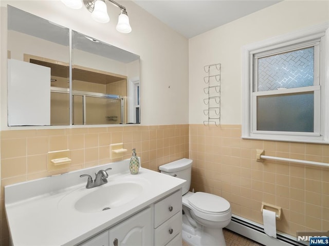 full bath with tile walls, baseboard heating, a shower stall, vanity, and toilet