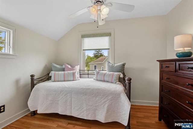 bedroom with baseboards, vaulted ceiling, multiple windows, and light wood-type flooring