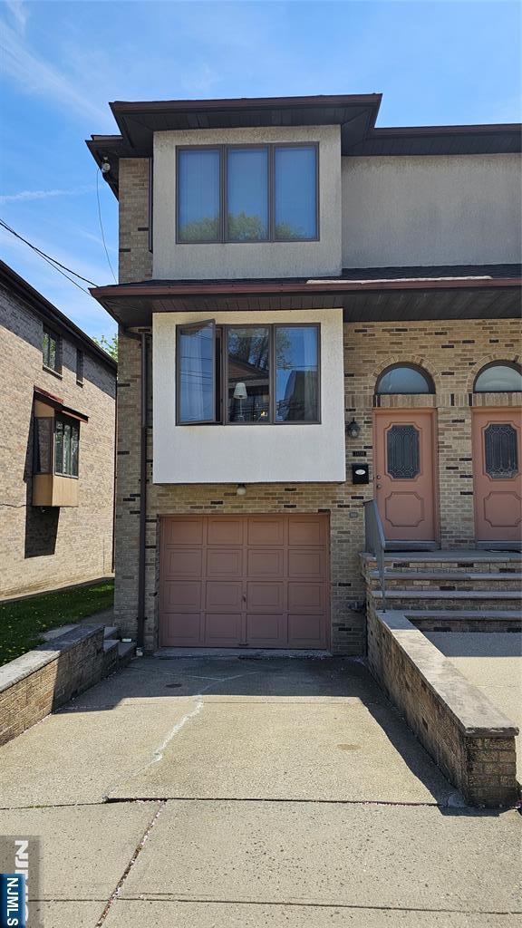 multi unit property featuring concrete driveway, brick siding, and a garage