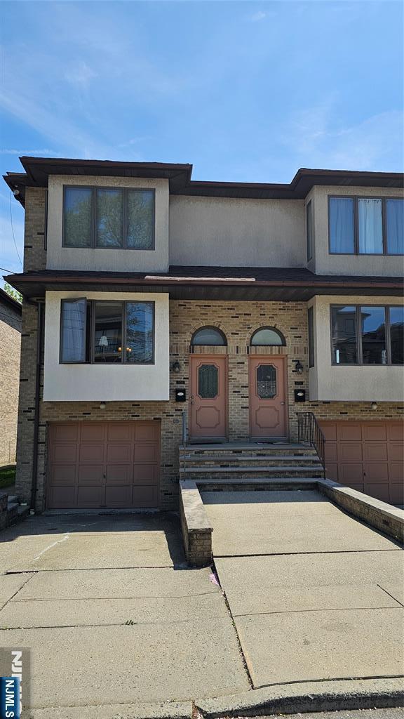 view of front facade featuring an attached garage, concrete driveway, and stucco siding