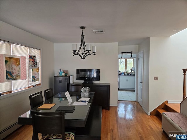 dining space featuring visible vents, a baseboard radiator, light wood-style floors, and an inviting chandelier