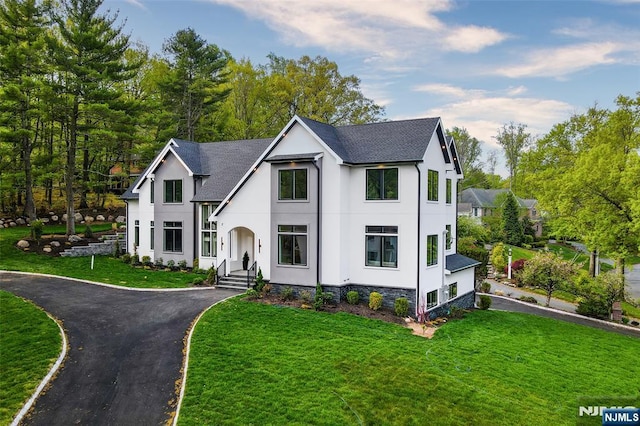 view of front of home featuring stucco siding, a garage, a front lawn, and aphalt driveway
