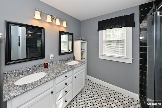 bathroom featuring double vanity, baseboards, a tile shower, and a sink