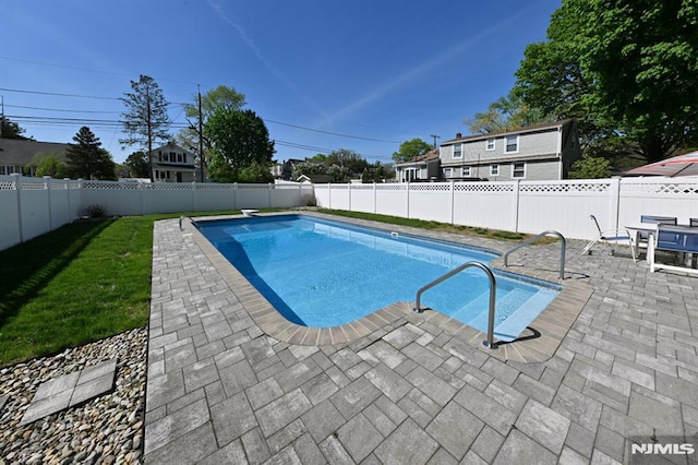 view of swimming pool featuring a patio, a fenced backyard, a lawn, and a fenced in pool