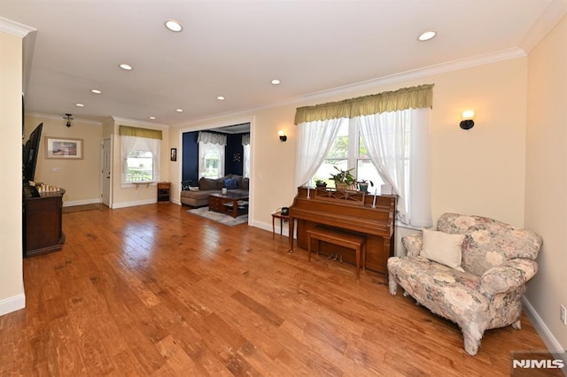 sitting room with light wood-style floors, ornamental molding, and recessed lighting