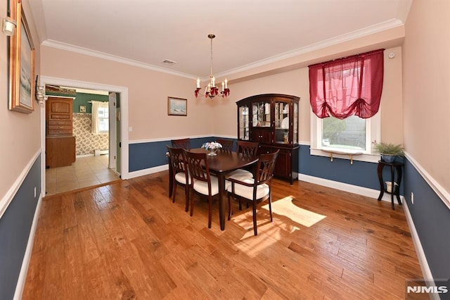 dining area with crown molding, visible vents, wood finished floors, baseboards, and a notable chandelier