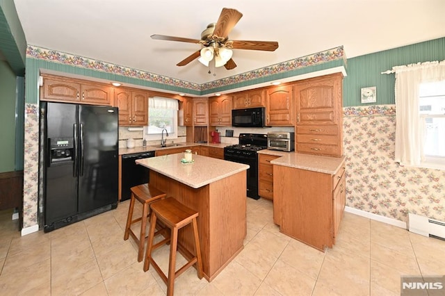 kitchen featuring light countertops, a sink, black appliances, and wallpapered walls