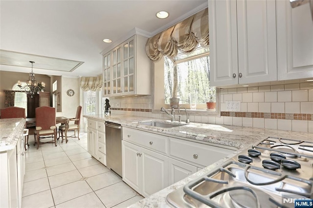 kitchen with stainless steel dishwasher, a sink, gas cooktop, light tile patterned floors, and tasteful backsplash