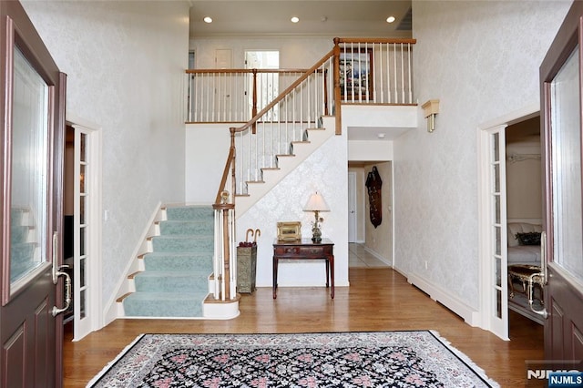 foyer with stairs, wood finished floors, a high ceiling, a textured wall, and baseboards