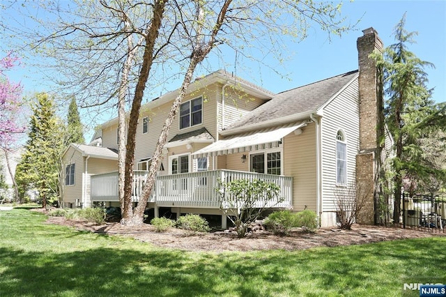 back of house with a chimney, a lawn, and a wooden deck
