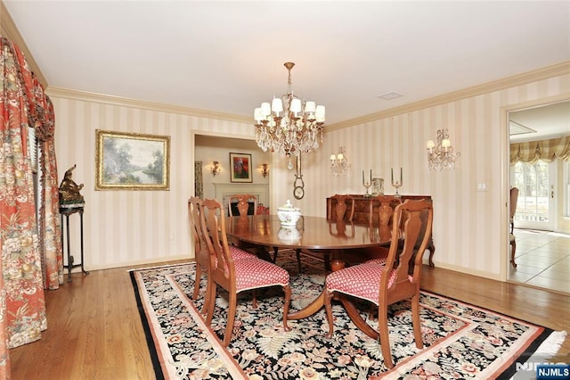 dining area with ornamental molding, a chandelier, light wood-style floors, wallpapered walls, and baseboards