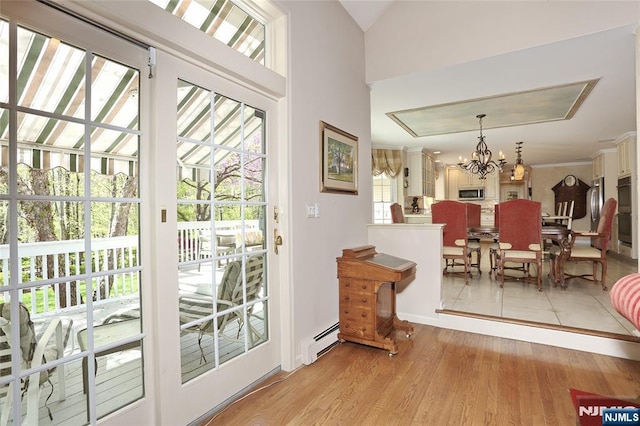 doorway featuring baseboard heating, a chandelier, and light wood finished floors