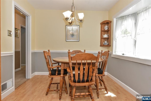 dining space with an inviting chandelier, light wood-style floors, baseboards, and visible vents