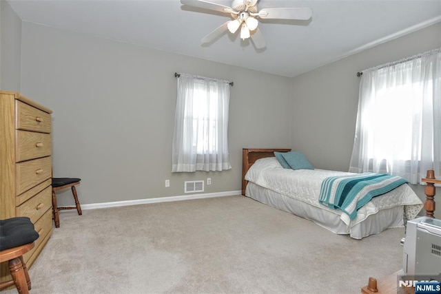 bedroom featuring light colored carpet, baseboards, visible vents, and ceiling fan