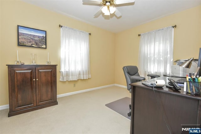 home office featuring baseboards, ceiling fan, and light carpet
