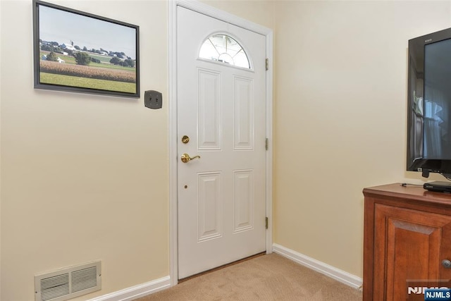 foyer entrance with baseboards, light colored carpet, and visible vents