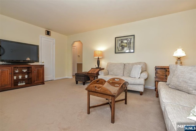 living room with baseboards, arched walkways, visible vents, and light carpet