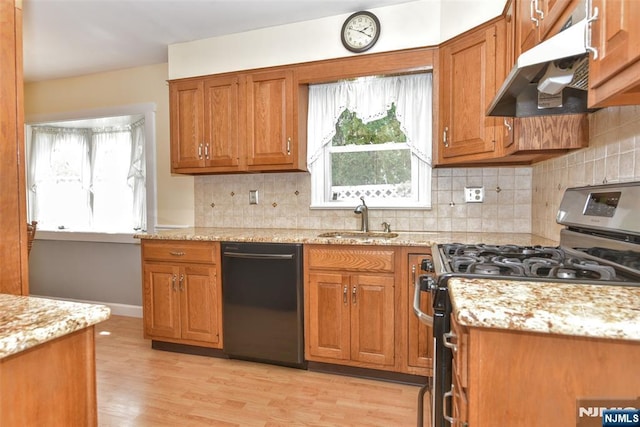 kitchen with stainless steel gas range oven, light wood-type flooring, a sink, under cabinet range hood, and black dishwasher
