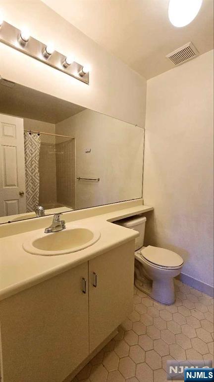 bathroom featuring visible vents, vanity, toilet, tile patterned floors, and a shower with curtain