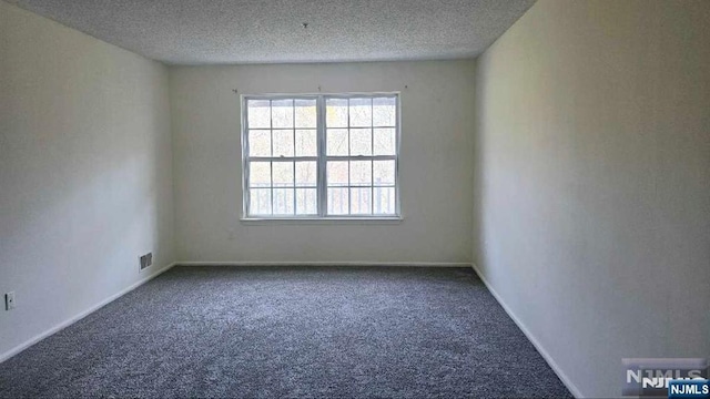 unfurnished room with carpet floors, baseboards, a textured ceiling, and visible vents