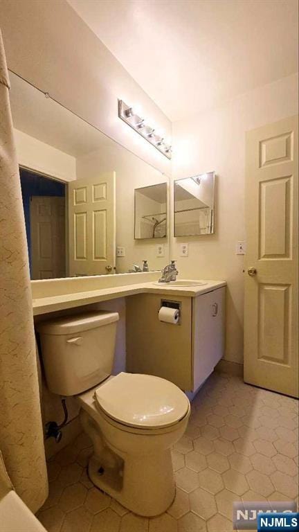 bathroom with toilet, a sink, and tile patterned flooring