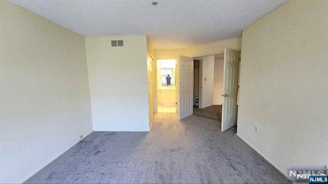 spare room with carpet, a textured ceiling, and visible vents