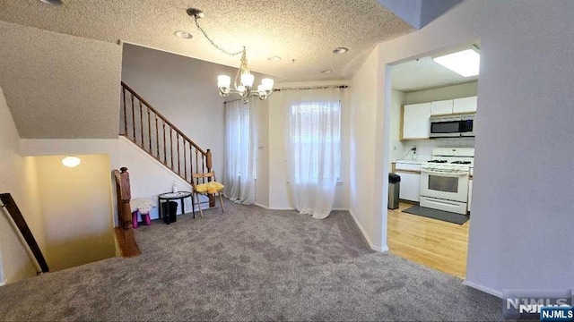 interior space featuring a textured ceiling, stairs, a notable chandelier, and light carpet