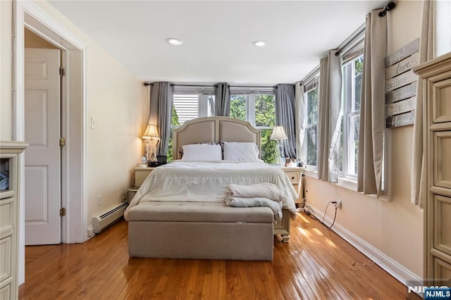 bedroom featuring a baseboard heating unit, light wood-type flooring, recessed lighting, and baseboards