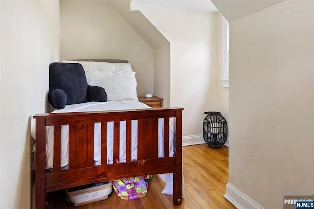 bedroom featuring light wood-style flooring, baseboards, and vaulted ceiling