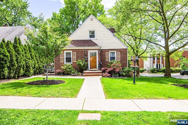 bungalow-style house with brick siding, a front yard, and roof with shingles