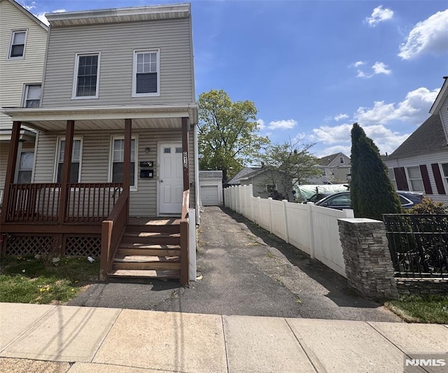 townhome / multi-family property with covered porch, fence, and aphalt driveway
